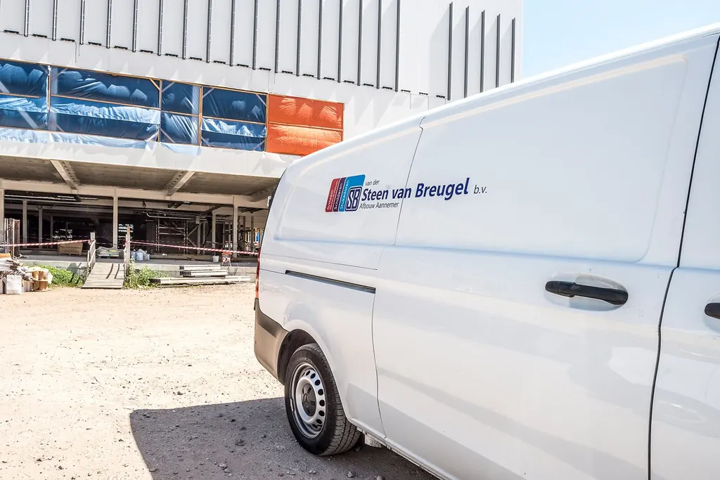 Bedrijfsbus van Van der Steen van Breugel op een bouwplaats voor een nieuw winkelpand