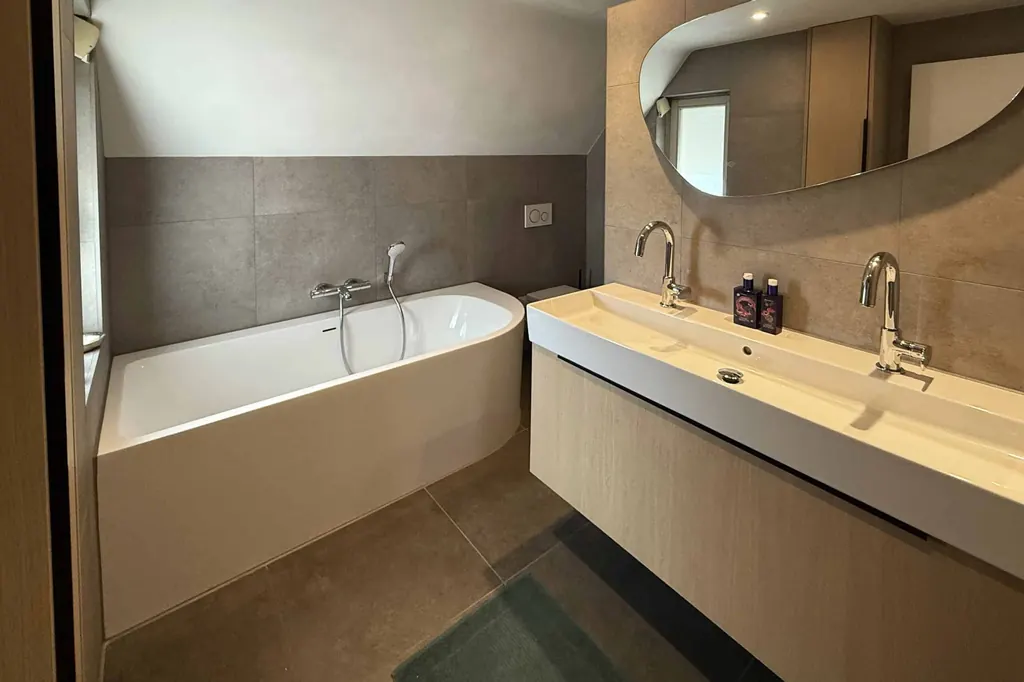 Nieuwe badkamer met ligbad, ruime wastafel en betonlook tegels