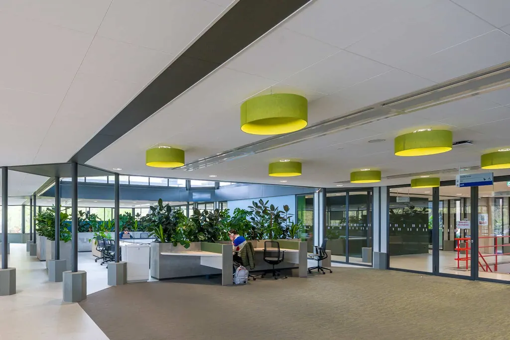 Open werkruimte met witte systeemplafonds en groene lampen in gebouw Neuron van de TU Eindhoven